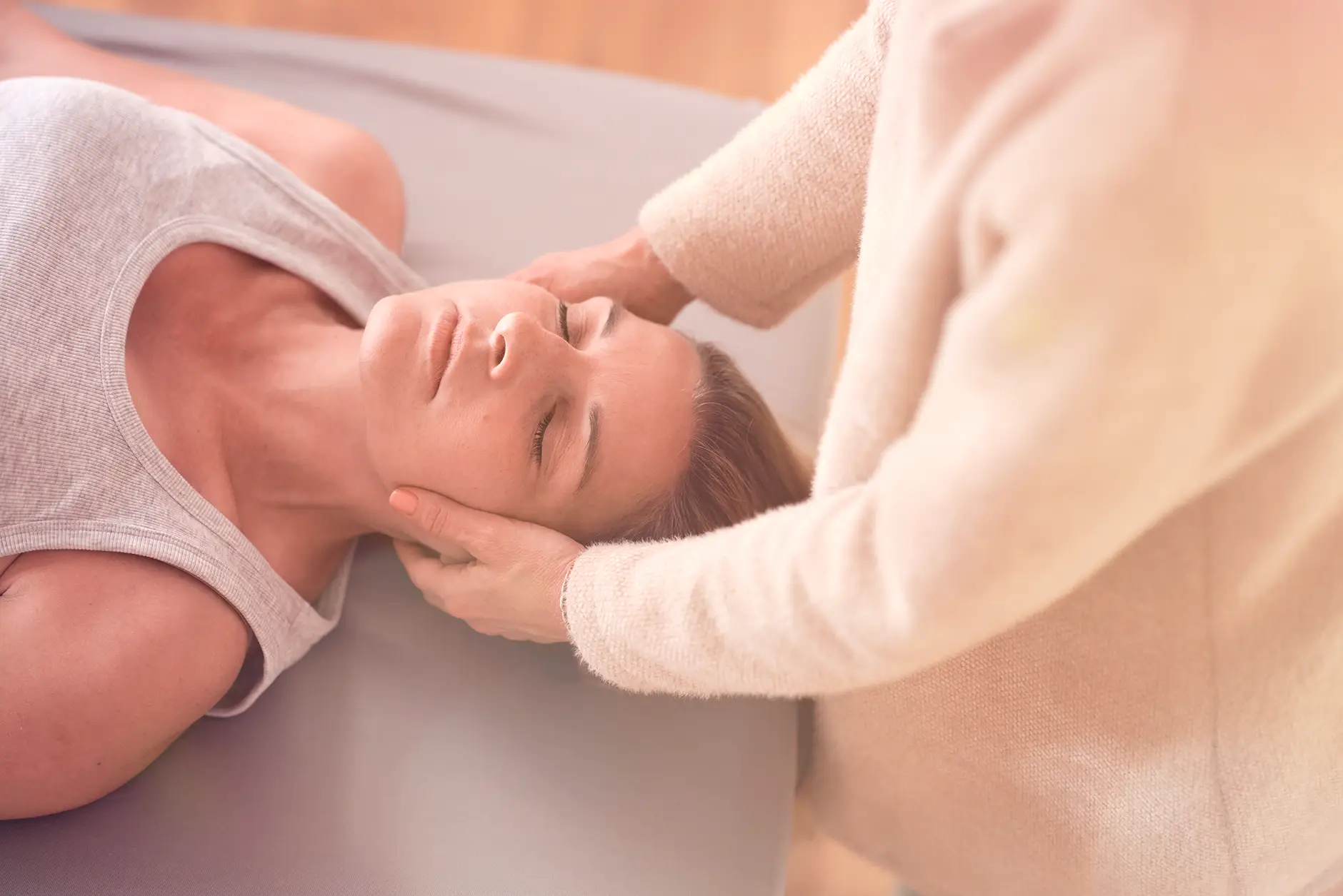 Janna Raphaela Odesser hält sanft den Kopf einer liegenden Patientin und unterstützt sie in einer körperorientierten Entspannungs- und Wahrnehmungsarbeit – achtsame therapeutische Begleitung in ruhiger Atmosphäre